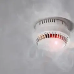 Czujka dymu piszczy, bo wykryła dym. Czerwona lampka sygnalizuje alarm.