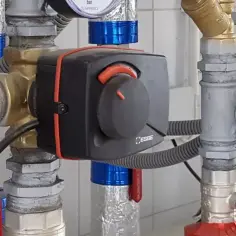 Montaż zaworów wody z termostatycznym regulatorem ESBE. Widoczne manometry i izolowane rury.
