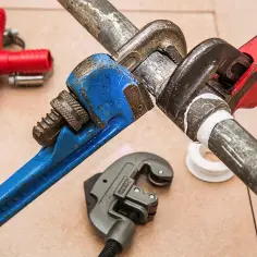 Narzędzia hydrauliczne i czerwony trójnik. Zastanawiasz się, ile kosztuje usługa hydraulika?