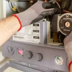 Rękawiczki technika przy kotle, kontrola ciśnienia w instalacji CO.