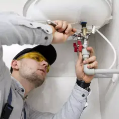 Instalator w okularach ochronnych montuje bojler. Zastanawiasz się, ile kosztuje wymiana bojlera?
