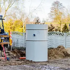 Trwa montaż centralnego ogrzewania. Koparka i rury czekają na instalację zbiornika.