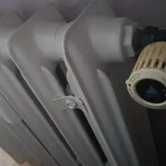 Biały grzejnik żeliwny z termostatem Danfoss. Awaria ogrzewania w Zabrzu? Zimno w mieszkaniu.