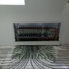 Instalacja ogrzewania podłogowego w Bielsku-Białej. Widoczny rozdzielacz i rury systemu.