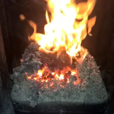 Żarzące się węgle i płomienie w piecu, pokazujące, jak palić miał w zwykłym piecu.