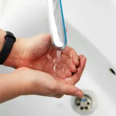 Dłonie łapią strumień wody z kranu, pokazując dobre ciśnienie wody w rurach.