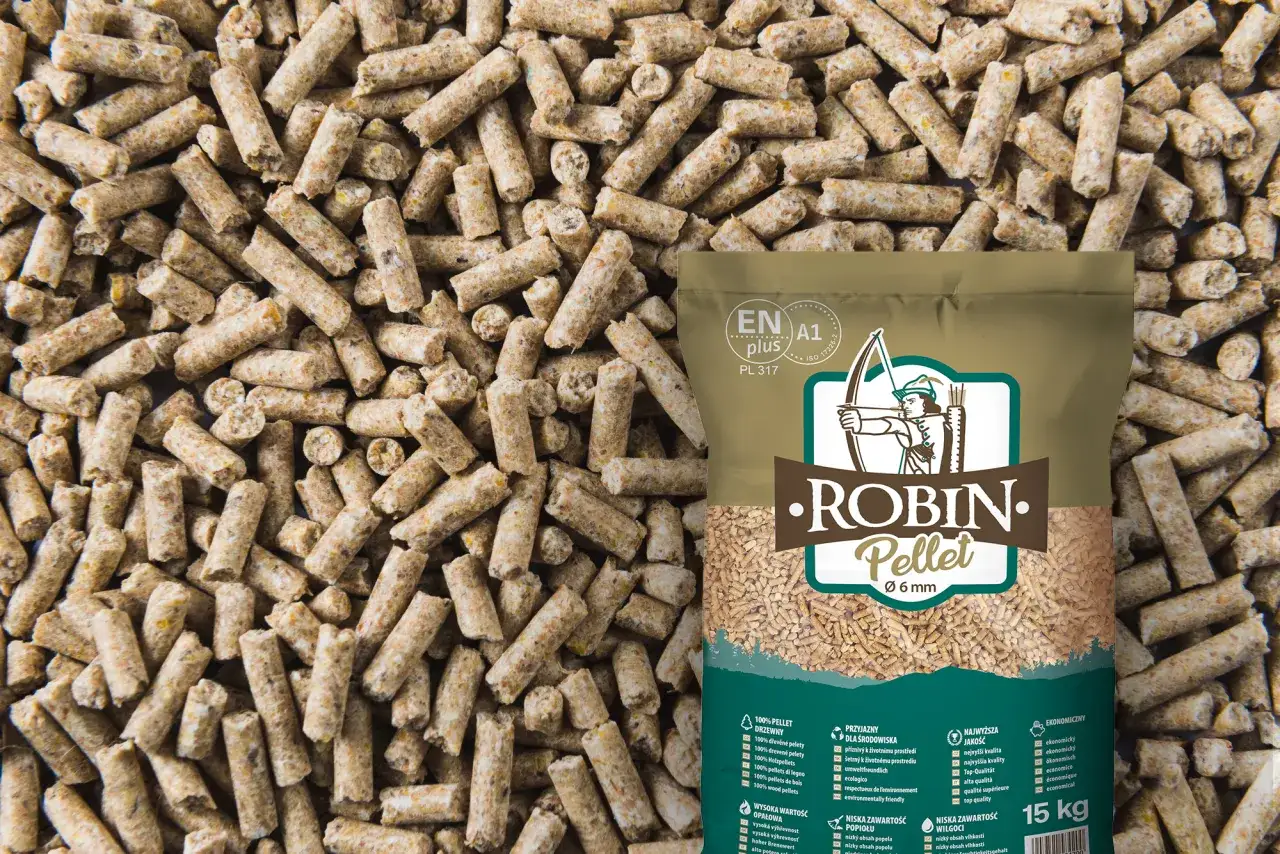 Worek z peletem drzewnym Robin Pellet 6 mm na tle rozsypanych granulek. Cena peletu zależy od jego jakości i składu.